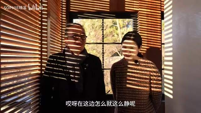 视频帧：木夕大里伙山酒店木百叶窗前，横纹光影打在谢柯与主持人身上