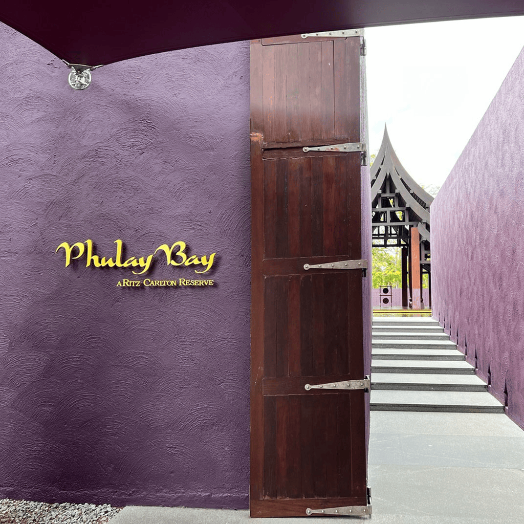 Phulay Bay 隐世酒店标志性的皇家紫（茄紫）色围墙入口，巨木大门对称构图
