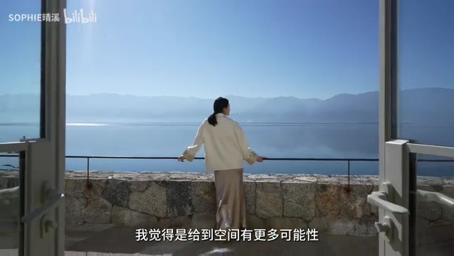 视频帧：青山村49号石砌露台，主持人背影面朝洱海